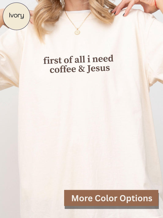 A person wearing a white t-shirt with the text "first of all I need coffee & Jesus" printed on it.