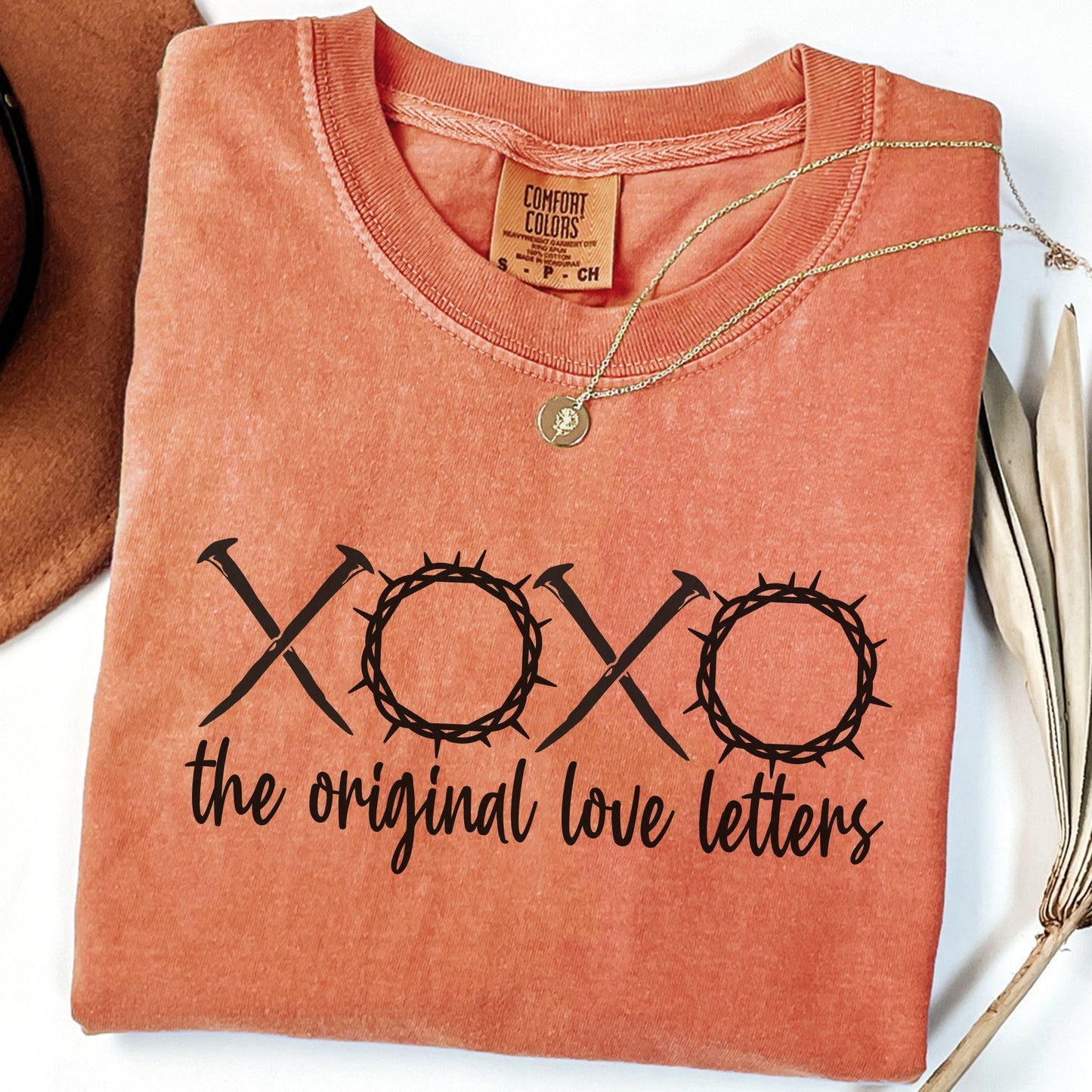 a red t-shirt with the text "XOXO the original love letters" printed on it, along with a necklace and some decorative elements.