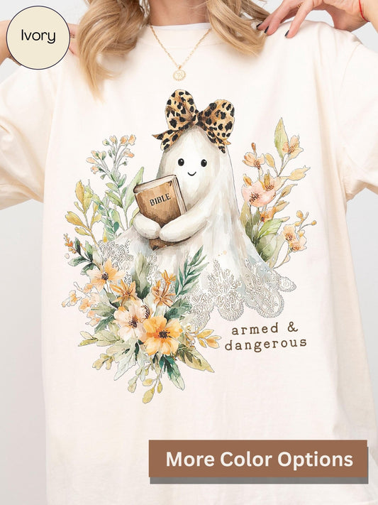 A person wearing a white t-shirt with a graphic design featuring a ghost holding a Bible and surrounded by flowers.