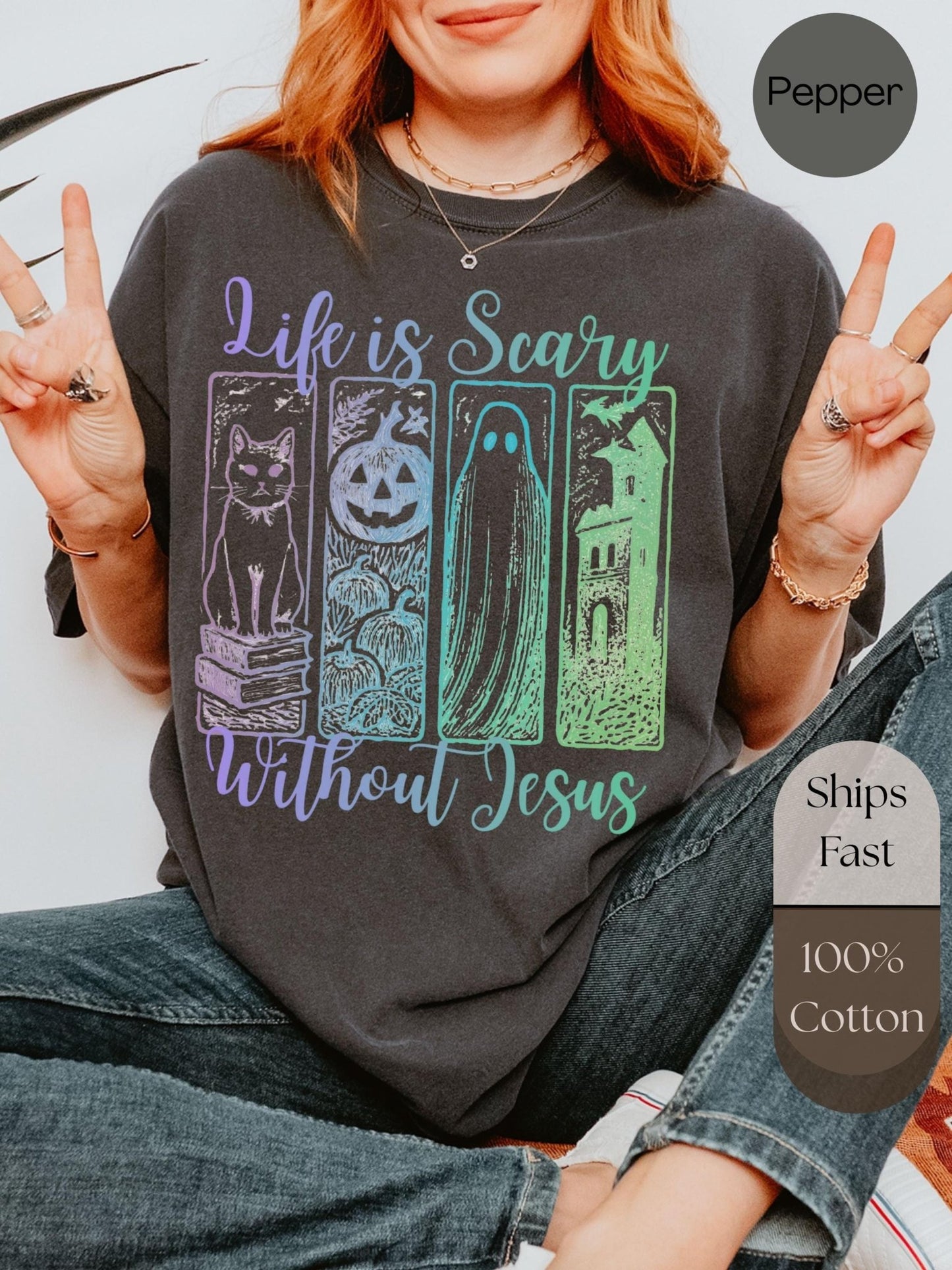 A person wearing a black t-shirt with a graphic design featuring a cat, a ghost, a pumpkin, and a house, along with the text &quot;Life is scary without Jesus&quot;.
