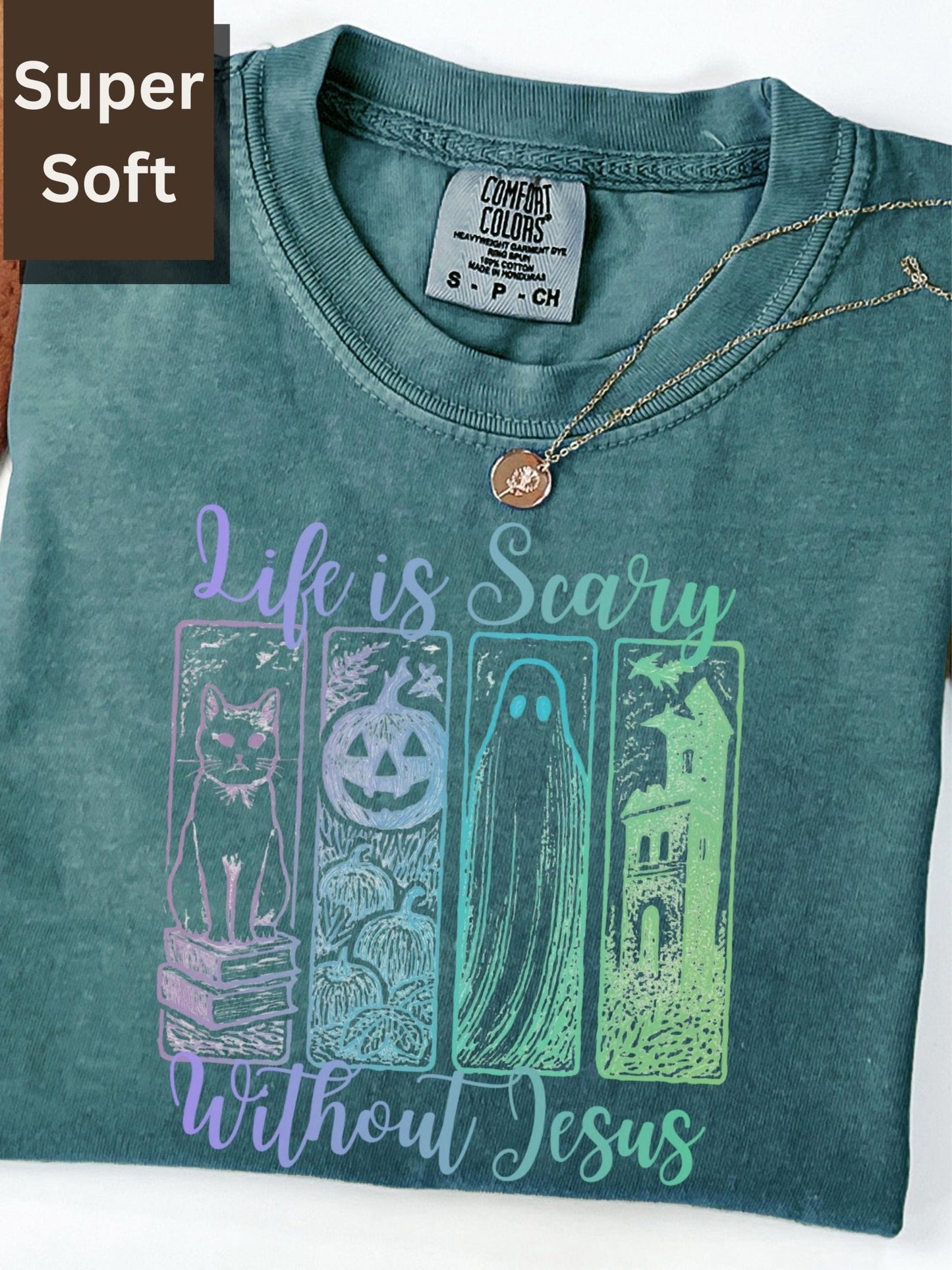 a green t-shirt with a graphic design featuring a cat, a pumpkin, a ghost, and a castle, along with the text &quot;Life is Scary Without Jesus&quot;.