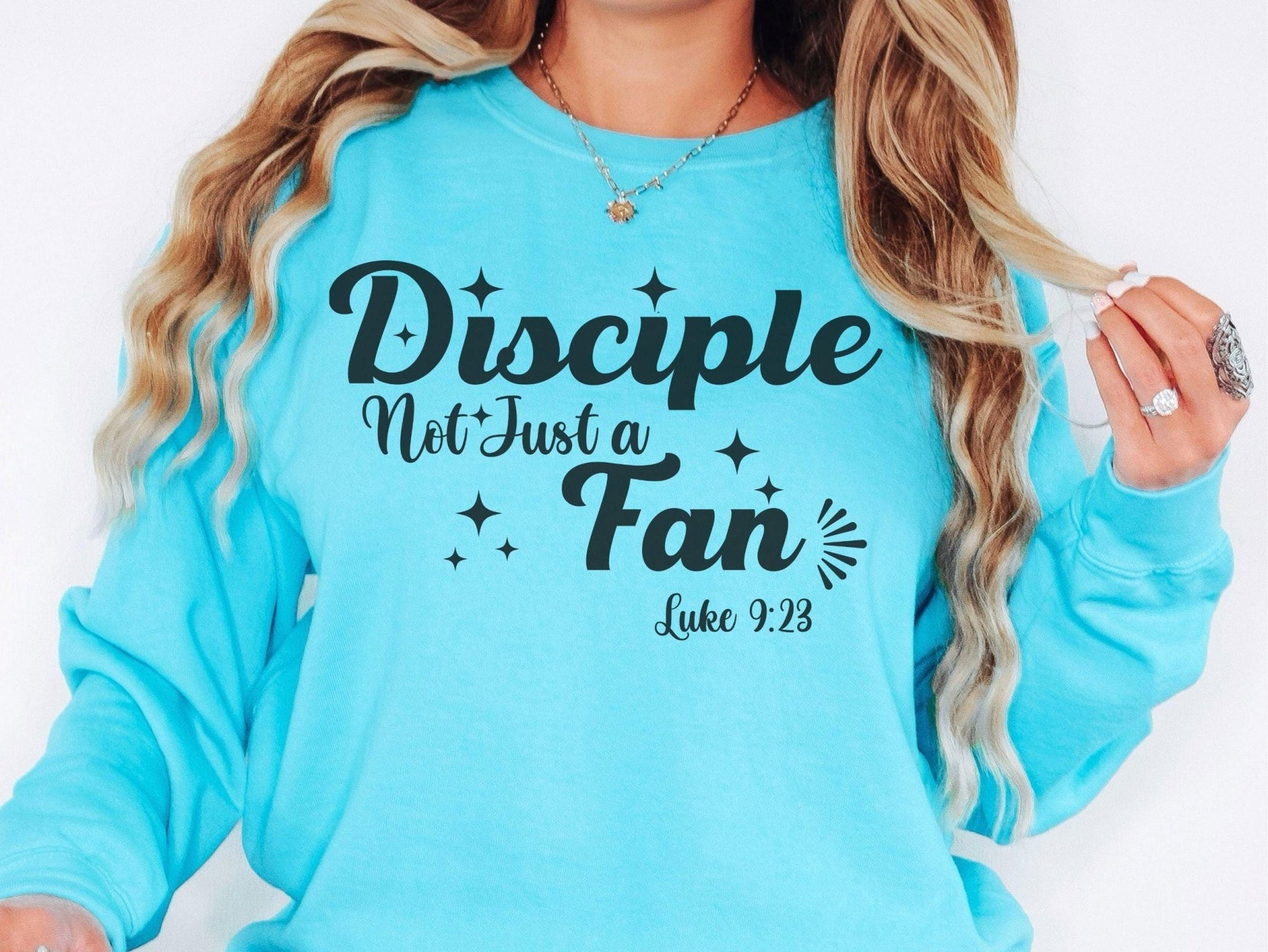 A woman wearing a blue long-sleeved shirt with the text &quot;Disciples Not Just Fans&quot; printed on it.