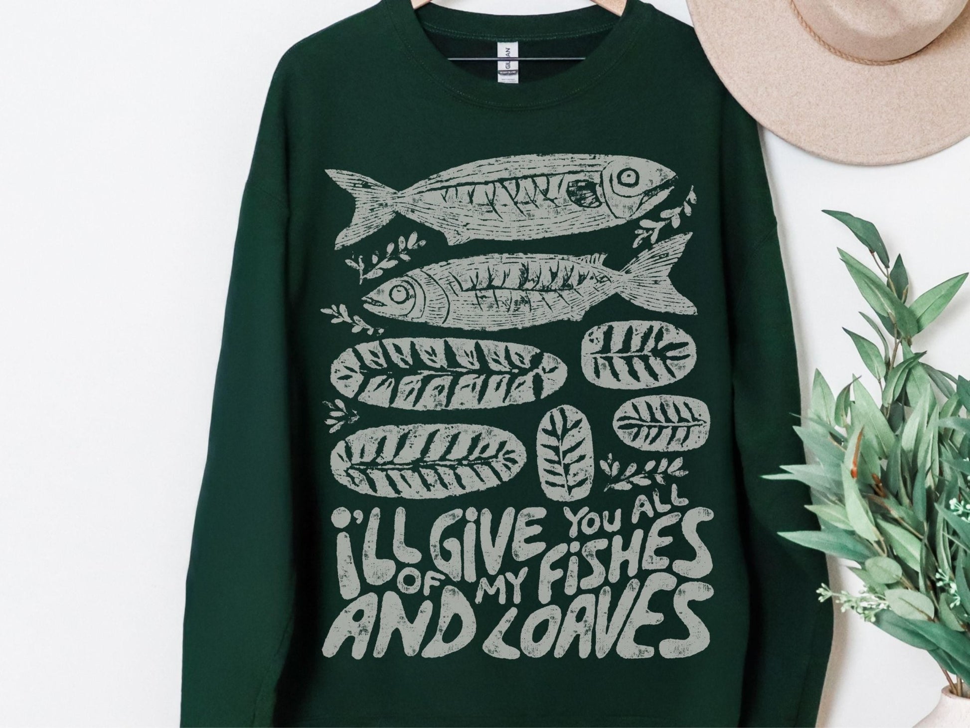A dark green sweatshirt with a graphic design of fish and leaves, along with the text &quot;I&#39;ll give you all of my fish and leaves&quot;.