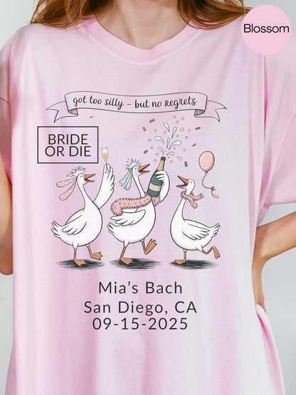 A pink t-shirt with a graphic design featuring three cartoon geese celebrating, along with text that reads &quot;got too silly - but no regrets&quot; and &quot;Mia&#39;s Bach San Diego, CA 09-15-2025&quot;.