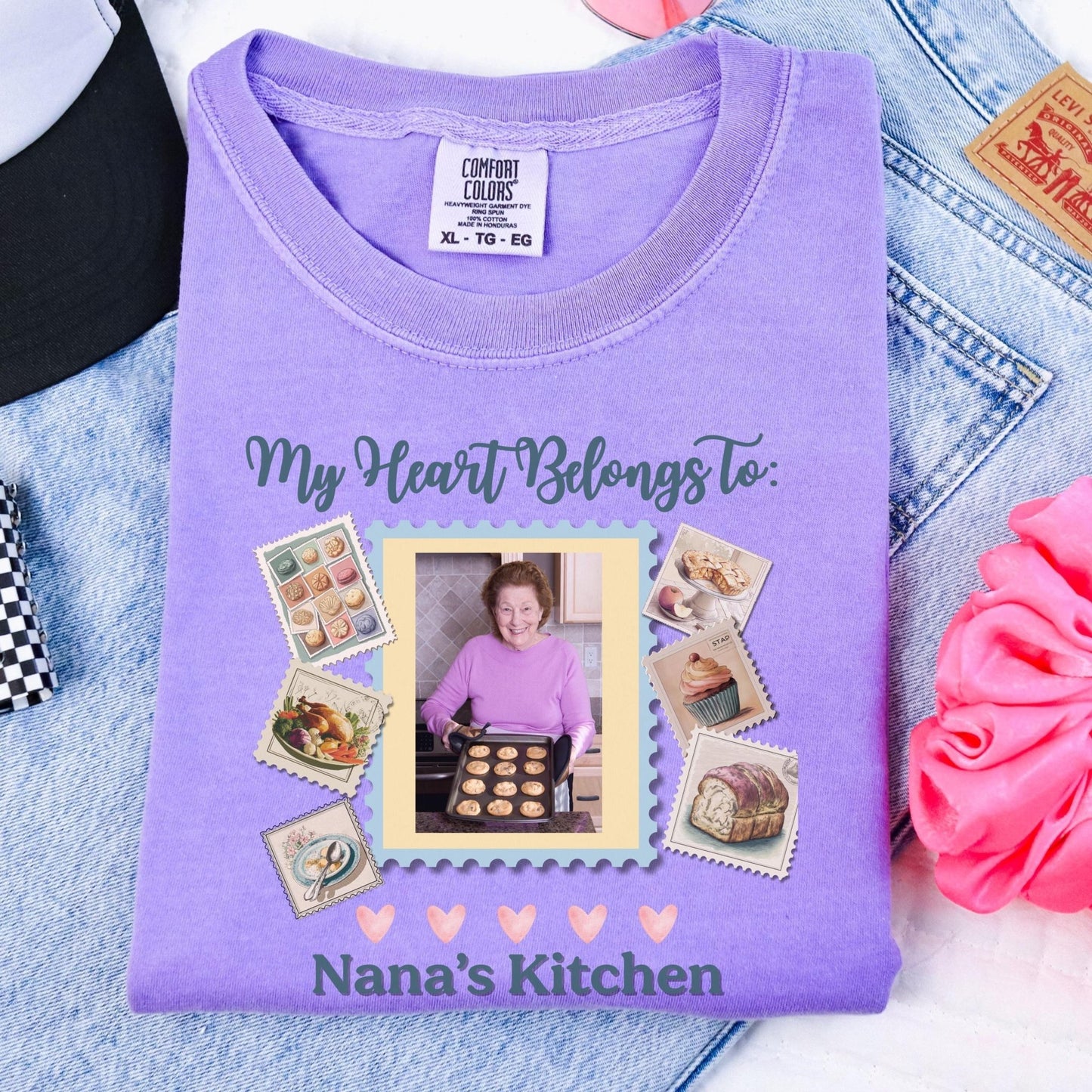 a purple t-shirt with a photo of a woman in a kitchen, surrounded by various kitchen-related items such as a cake, a bowl, and a spoon.