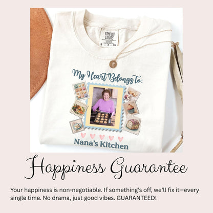 a white t-shirt with a personalized design, including a photo of a woman and various food items. The text on the t-shirt reads &quot;My Heart Belongs to: Nana&#39;s Kitchen&quot; and &quot;Happiness Guarantee&quot;.