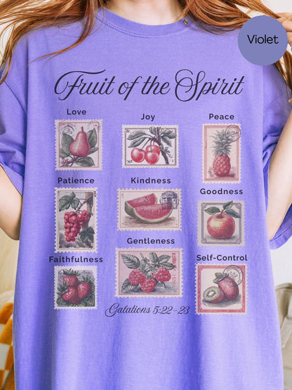 A person wearing a purple t-shirt with a graphic design depicting various fruits and their associated spiritual qualities.