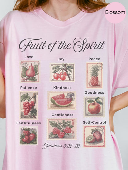 A person wearing a pink t-shirt with a graphic design depicting the fruit of the spirit and its associated values.