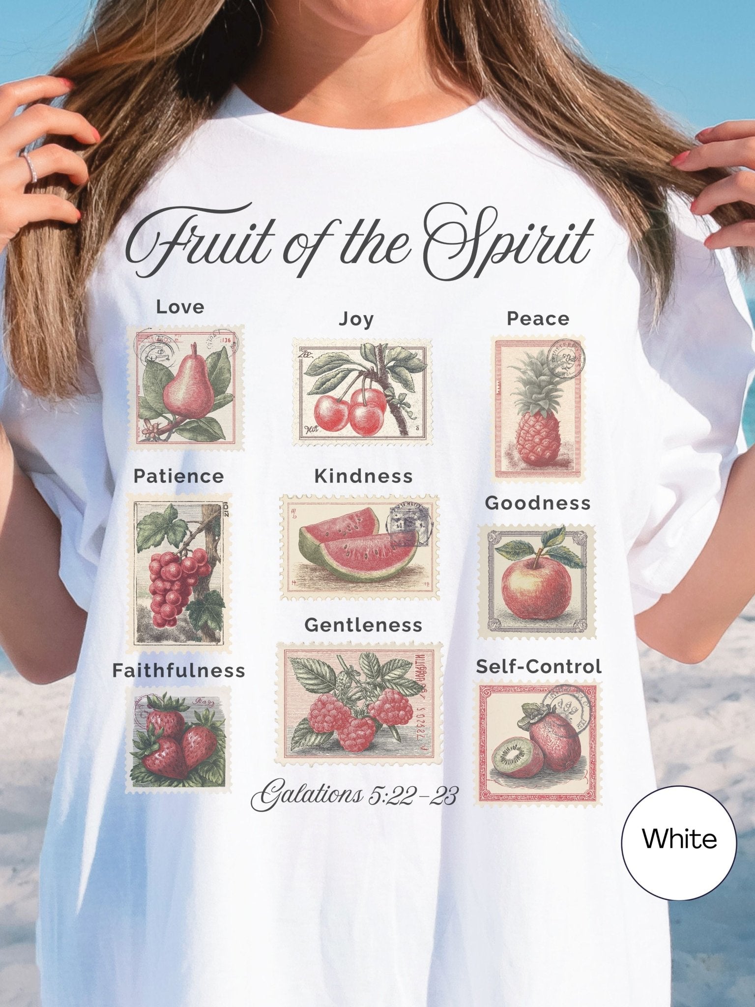 A white t-shirt with a graphic design depicting various fruits and the text "Fruit of the Spirit" along with their corresponding Bible verse numbers.