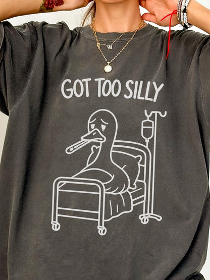 A person wearing a gray t-shirt with a graphic of a cartoon duck in a hospital bed and the text &quot;GOT TOO SILLY&quot; printed on it.