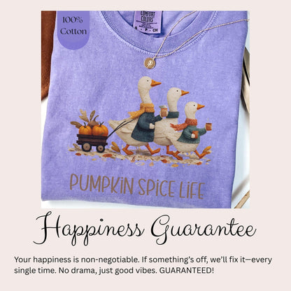 A purple t-shirt with a graphic of three white ducks walking on a path, carrying pumpkins, and the text &quot;PUMPKIN SPICE LIFE&quot; printed on it.