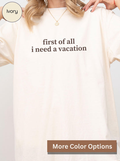 A person wearing a white t-shirt with the text "first of all I need a vacation" printed on it.