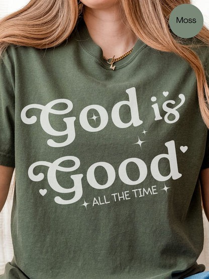 A woman wearing a green t-shirt with the text "God is Good All the Time" printed on it.
