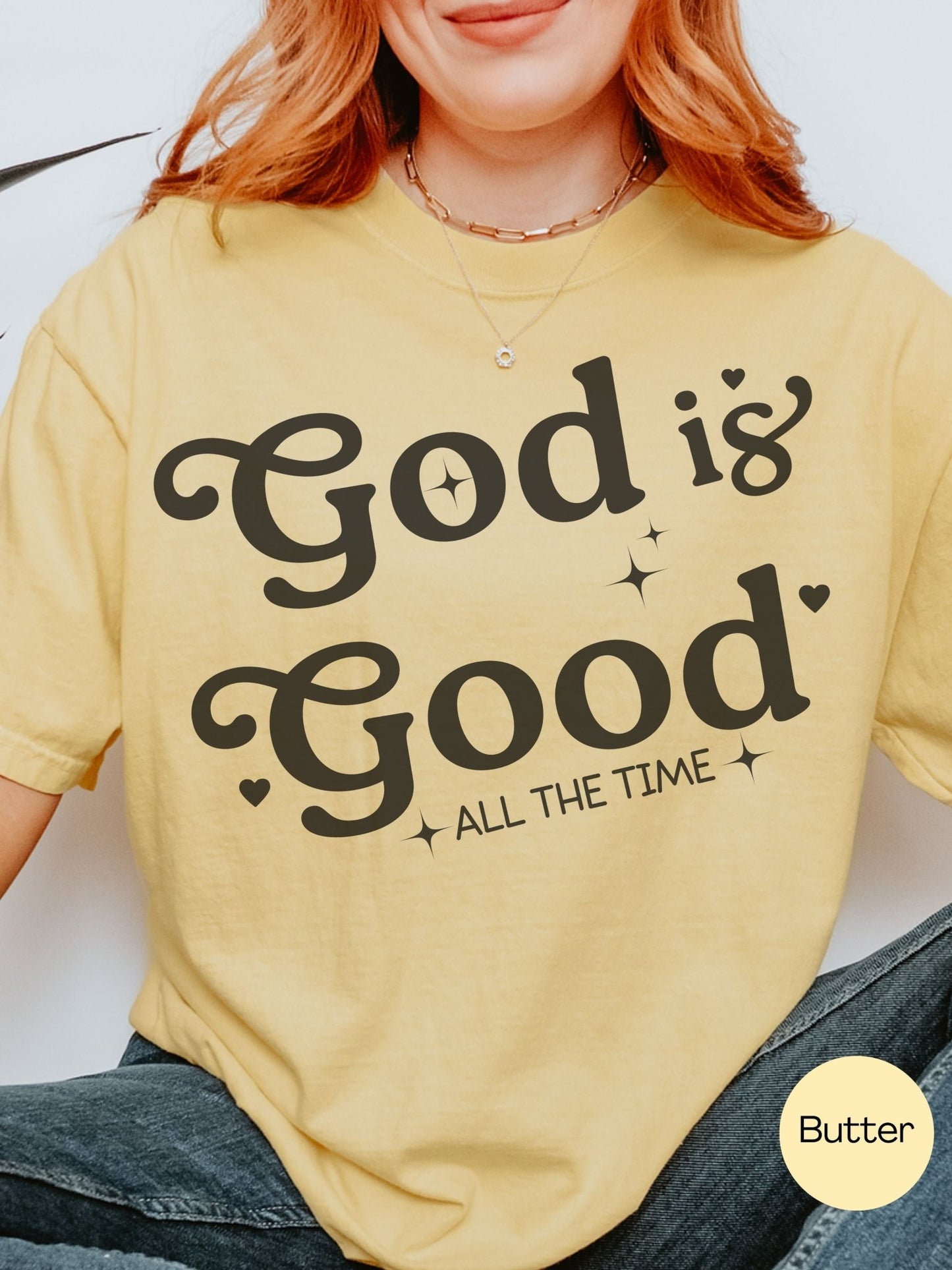 A woman wearing a yellow t-shirt with the text "God is Good All the Time" printed on it.