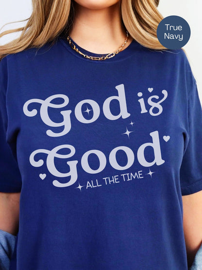 A woman wearing a navy blue t-shirt with the text "God is Good All the Time" printed on it.