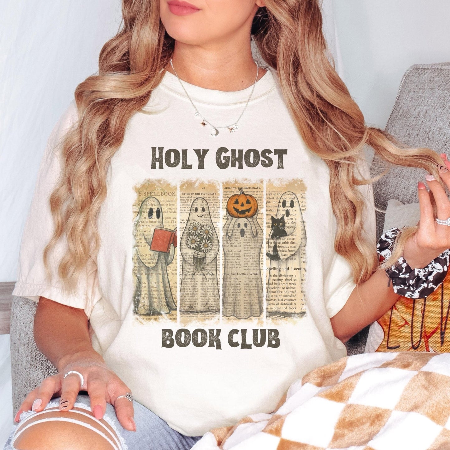 A woman wearing a white t-shirt with a graphic design featuring four ghost characters and the text "HOLY GHOST BOOK CLUB".