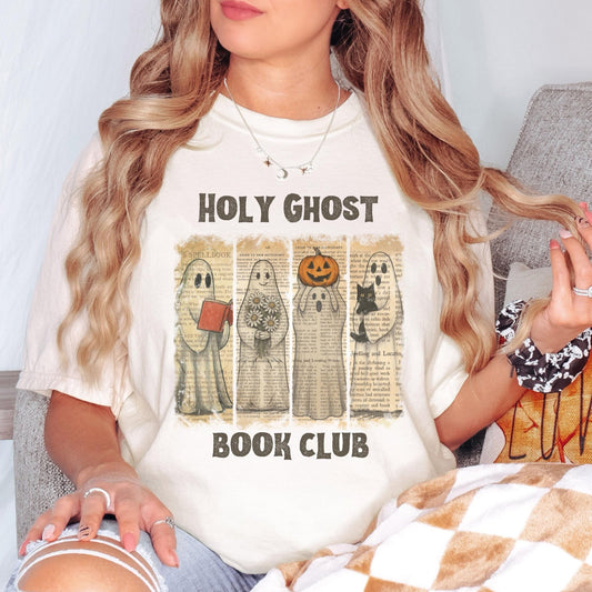 A woman wearing a white t-shirt with a graphic design featuring four ghost characters and the text "HOLY GHOST BOOK CLUB".