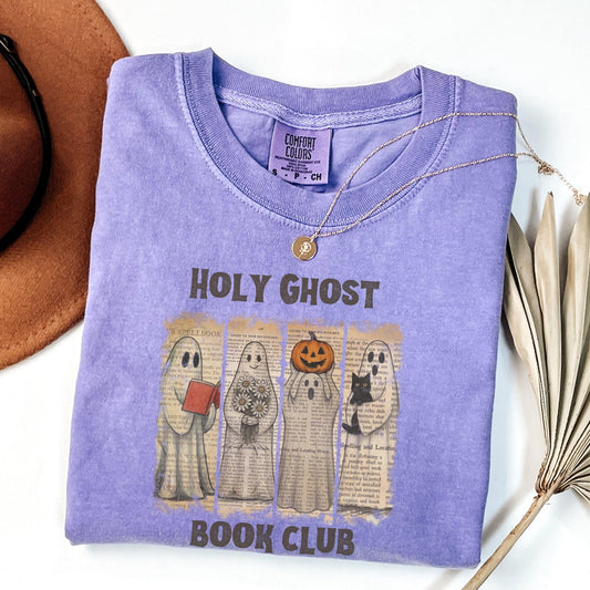 A purple t-shirt with a graphic design featuring four ghost characters and the text "HOLY GHOST BOOK CLUB" printed on it.