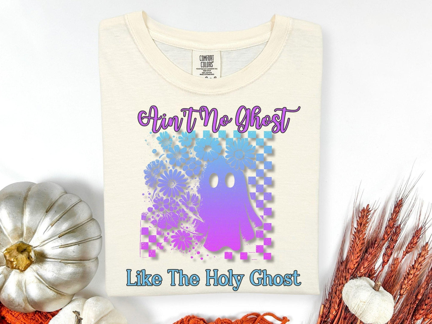 a white t-shirt with a graphic design of a purple and blue ghost surrounded by flowers, along with the text "Ain't No Ghost Like The Holy Ghost".