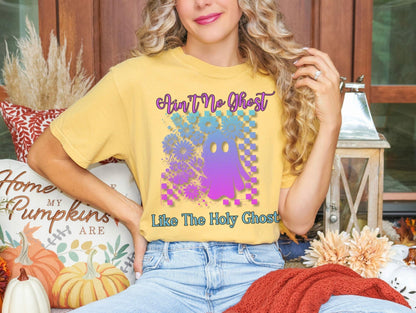 A woman wearing a yellow t-shirt with a graphic of a ghost and text, sitting on a bench surrounded by fall decorations.