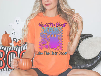 A woman wearing an orange t-shirt with a graphic of a purple and blue ghost, holding a mug and surrounded by Halloween decorations.