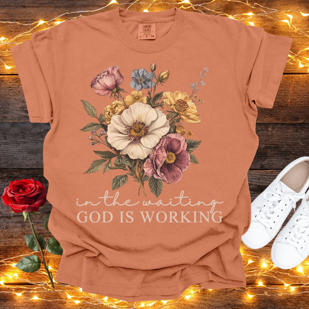 a t-shirt with a floral design, a pair of white sneakers, and a red rose, all placed on a wooden surface with twinkling lights in the background.