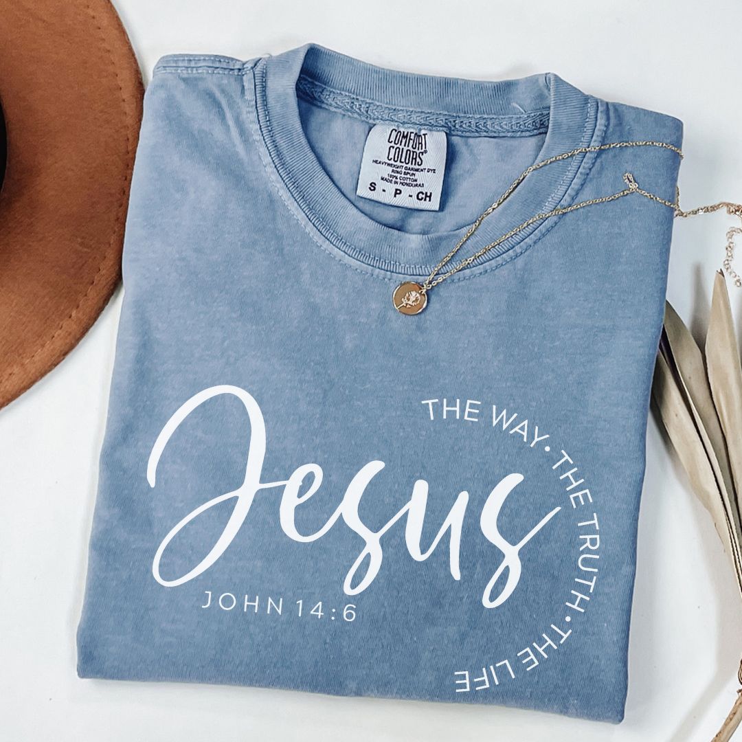A blue t-shirt with white text and a gold necklace are displayed on a white surface.