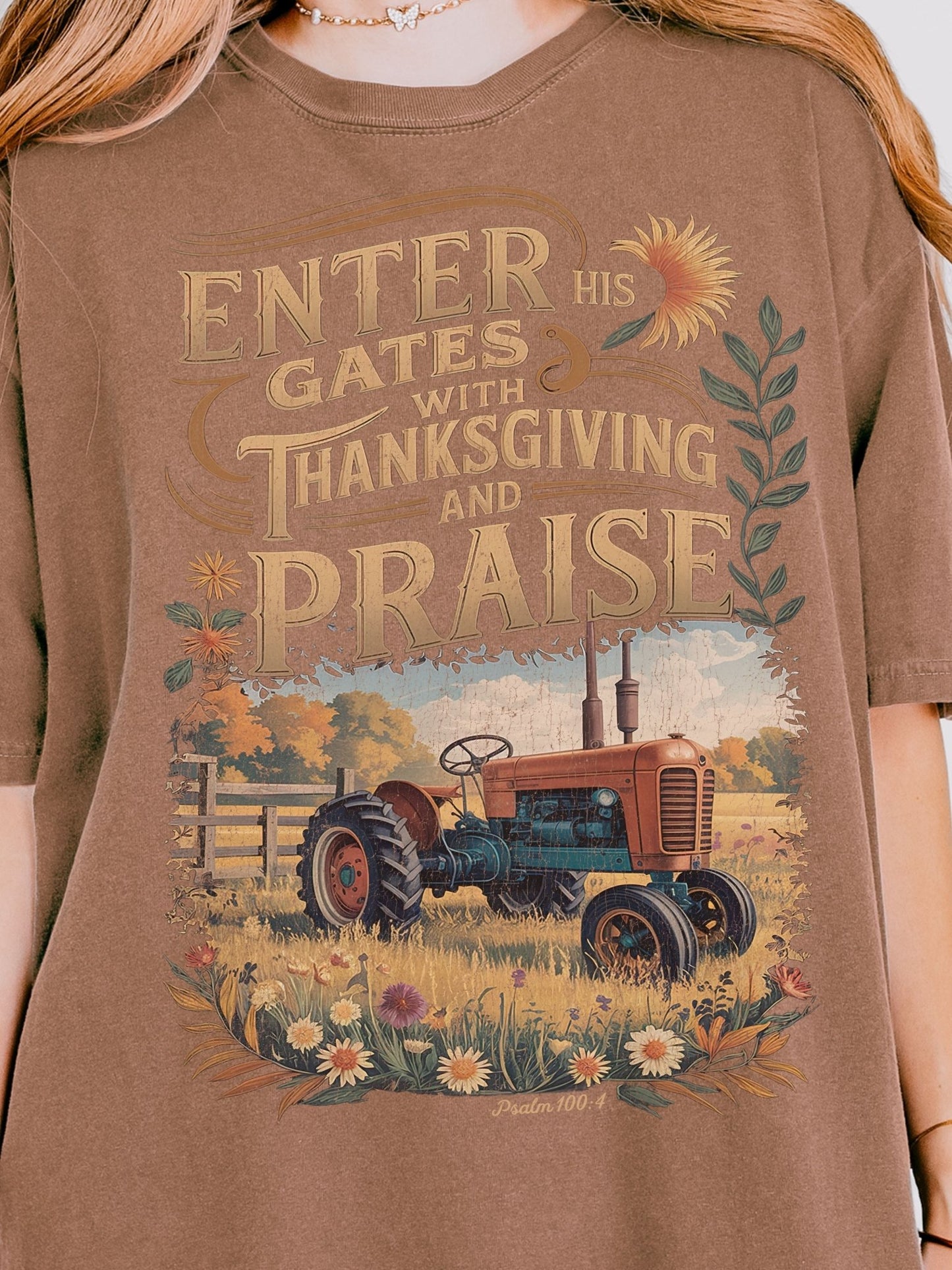 a t-shirt with a graphic design depicting a tractor in a field with flowers and a sunflower.