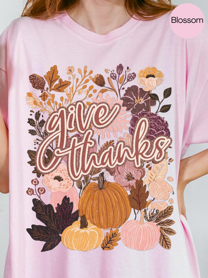 A pink t-shirt with a floral design and the text &quot;Give Thanks&quot; printed on it.