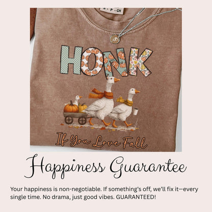 a t-shirt with a graphic design depicting three white geese walking on a wagon pulled by a pumpkin carriage, with the word &quot;HONK&quot; written on the t-shirt. Below the image, there is text that reads &quot;If You Love Fall&quot; and &quot;Happiness Guarantee&quot;, along with a guarantee that if something goes wrong, the guarantee will fix it every single time, with no drama and just good vibes.