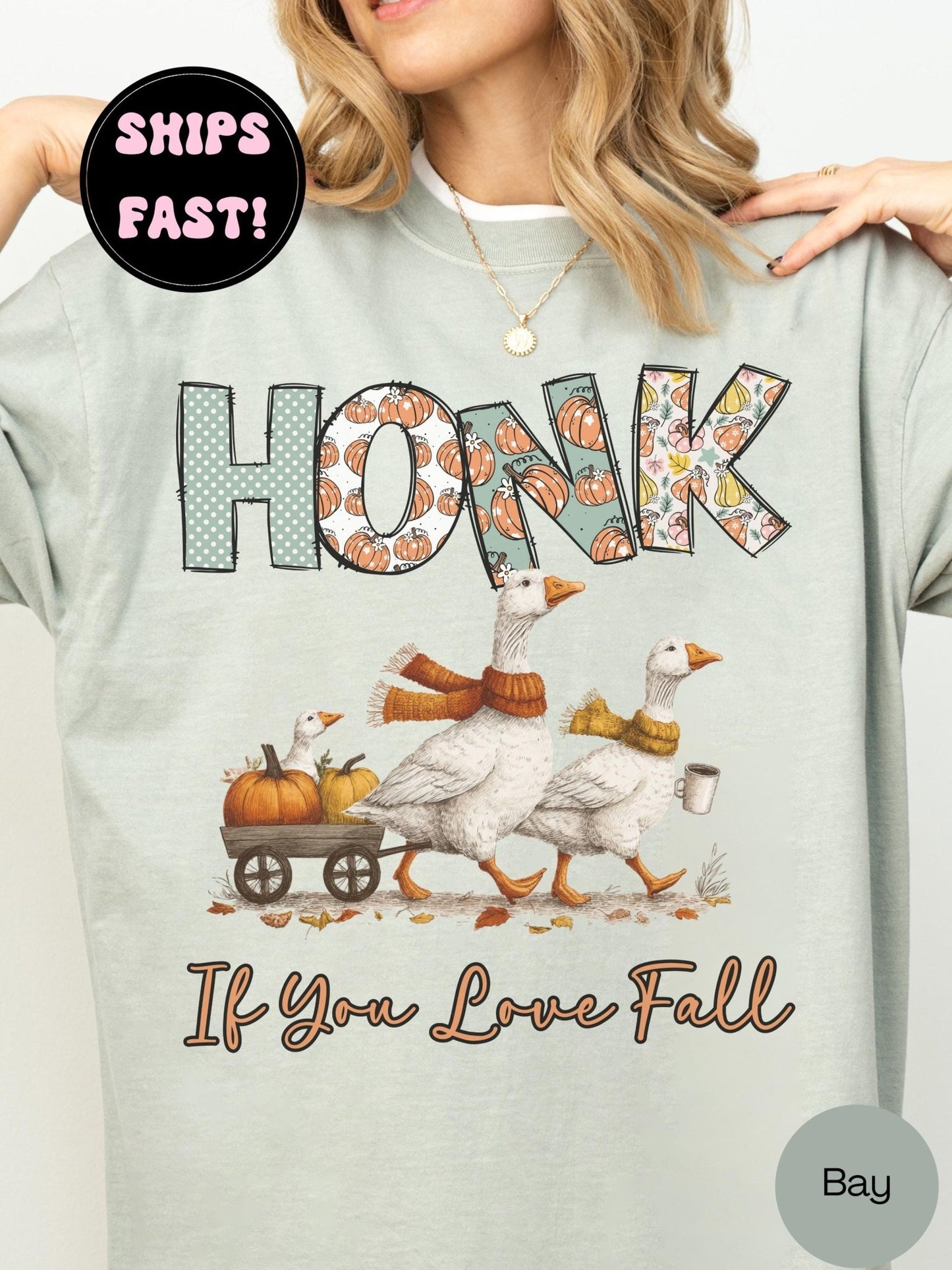 A woman wearing a gray t-shirt with a graphic design featuring a group of geese and pumpkins, along with the text &quot;HONK&quot; and &quot;If You Love Fall&quot;.