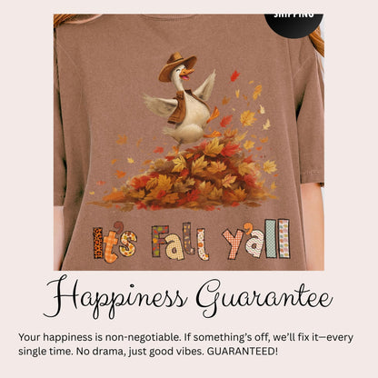 A t-shirt with a cartoon goose wearing a cowboy hat and surrounded by autumn leaves, with the text &quot;It&#39;s Fall Y&#39;all&quot; and a message about the guarantee of happiness.