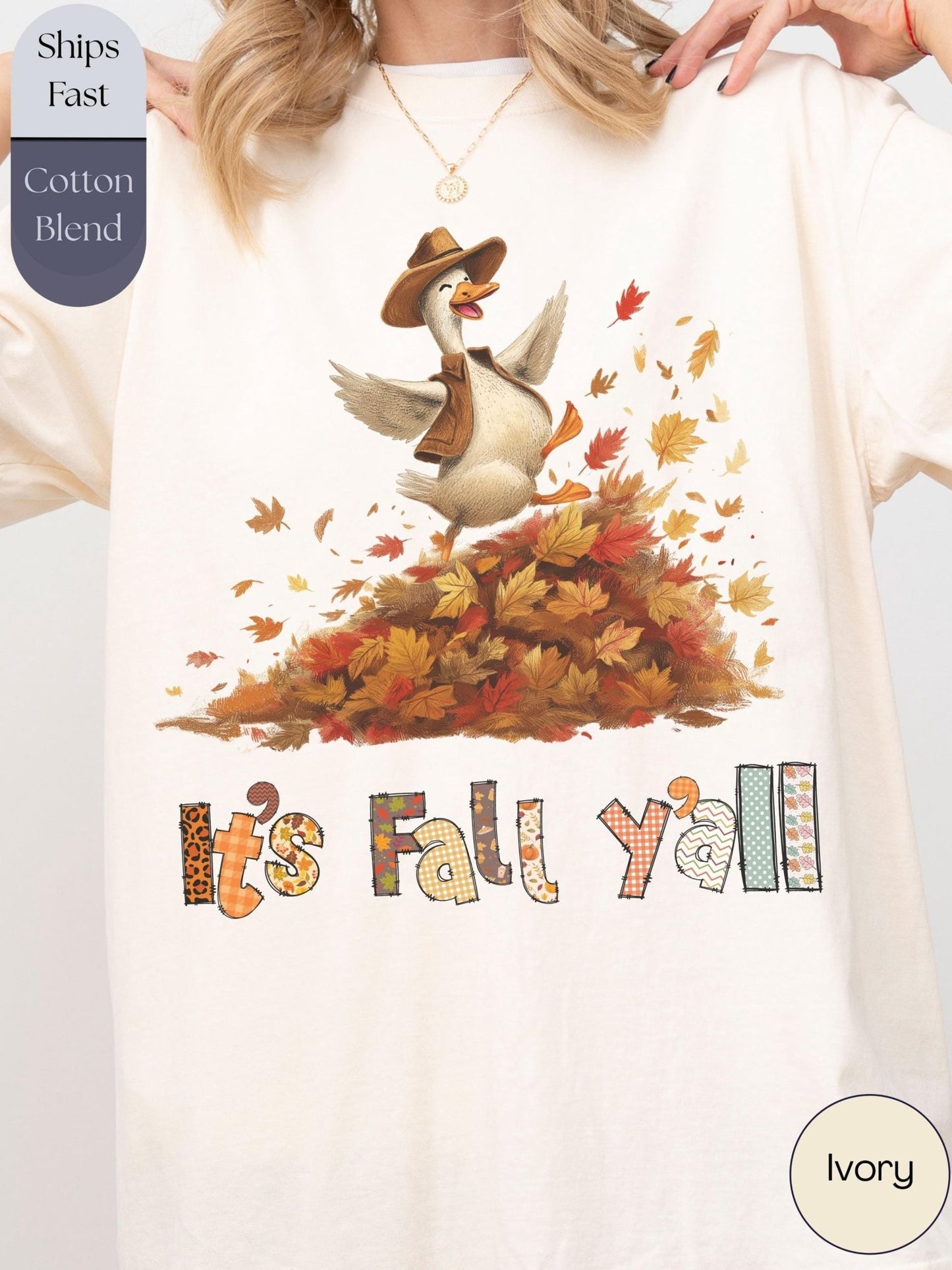 A person wearing a white t-shirt with a graphic design depicting a cartoon goose surrounded by autumn leaves and the text &quot;It&#39;s Fall y&#39;all&quot;